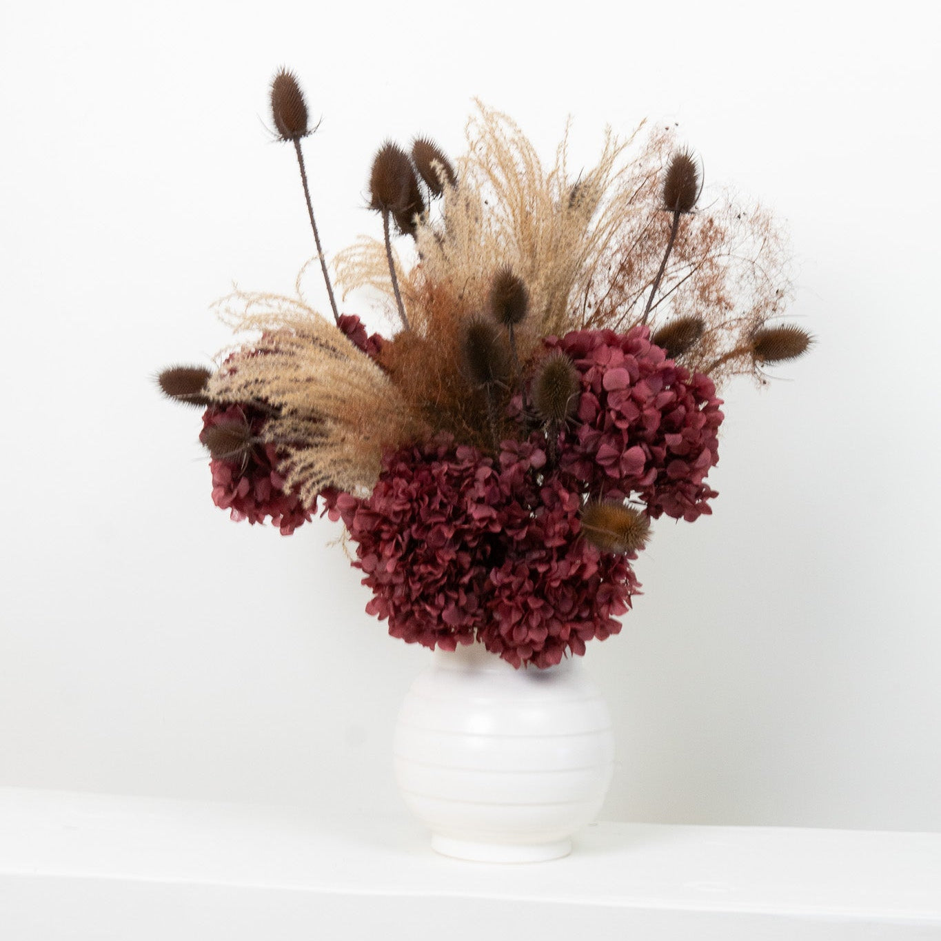 Bouquet of dried flowers in a white vase on a white background