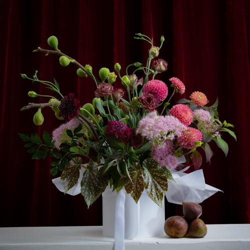 Bouquet of flowers in a white vase on a dark red curtain background