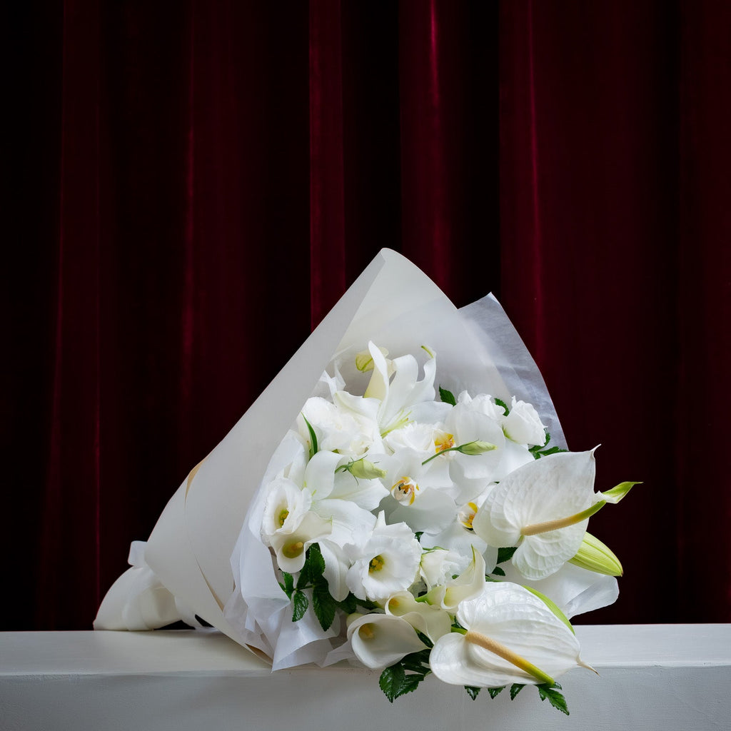 Bouquet of white flowers on a gray surface with a dark red curtain background