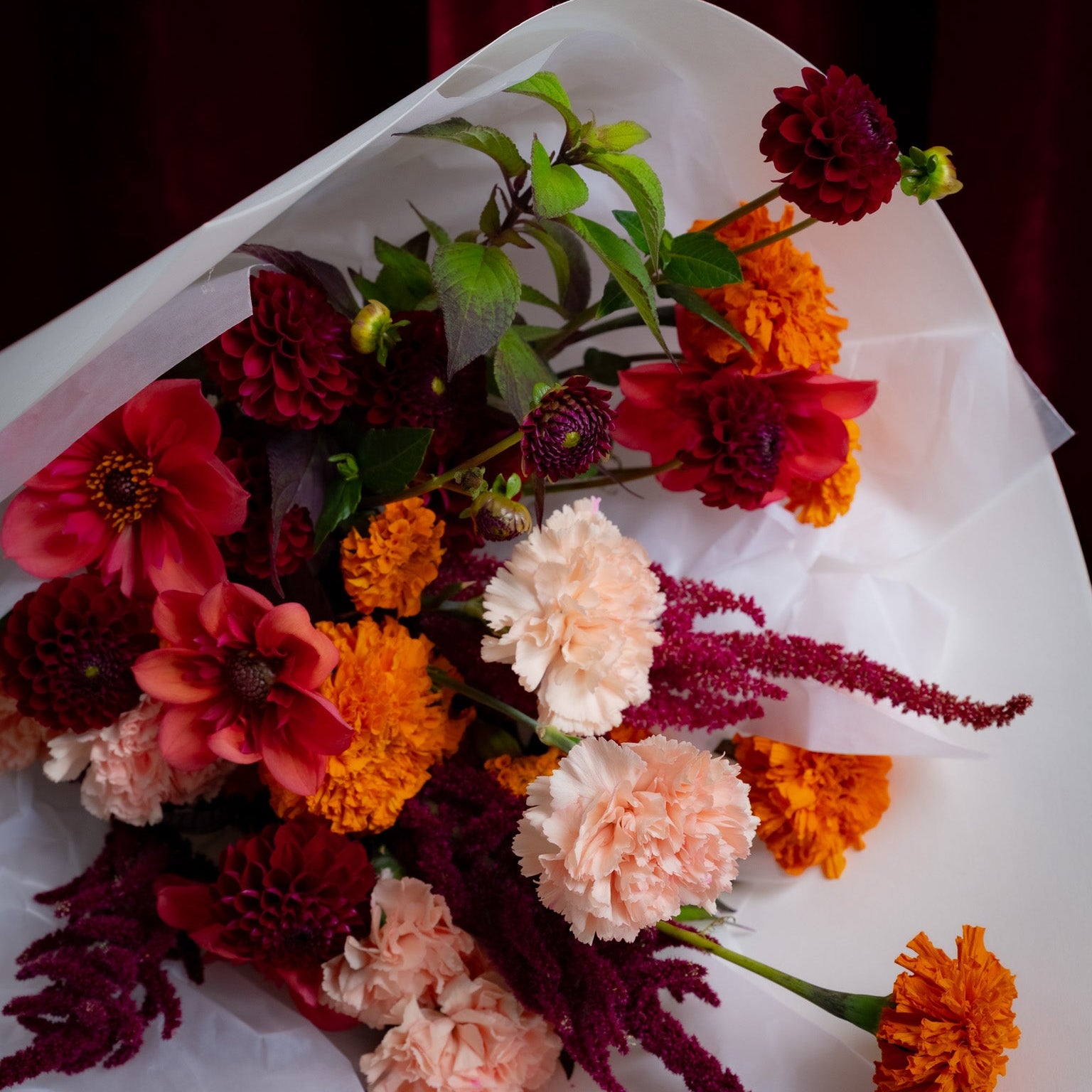 Bouquet of flowers with red, orange, and pink colors on a white surface.